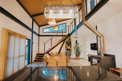a dining room with a table and a staircase in a house at Casa Brunia Lago Los Molinos in Villa General Belgrano