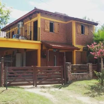 a house with a wooden fence in front of it at Departamento CatyDay in Mina Clavero