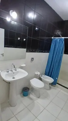a bathroom with a sink and a toilet and a blue shower curtain at LOS BULGAROS in Villa Cura Brochero