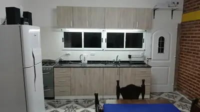 a kitchen with wooden cabinets and a black cat sitting at a table at LOS BULGAROS in Villa Cura Brochero