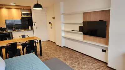 a living room with a dining room table and a flat screen tv at Centro Av General Paz 418 Estacionamiento economico in Cordoba