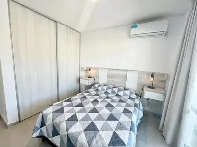 a bedroom with a bed with a black and white quilt at Torre Leonardo Carlos Paz in Villa Carlos Paz