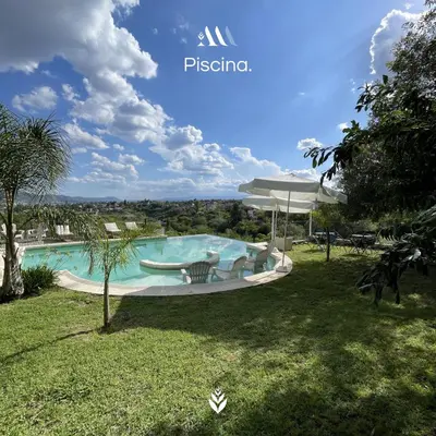 a swimming pool with chairs and an umbrella in a yard at Agrippina in Villa Carlos Paz