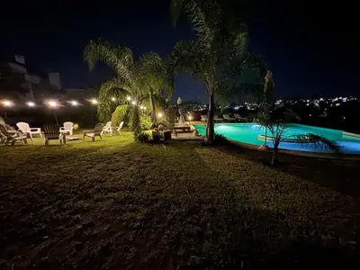 a swimming pool at night with chairs and palm trees at Agrippina in Villa Carlos Paz