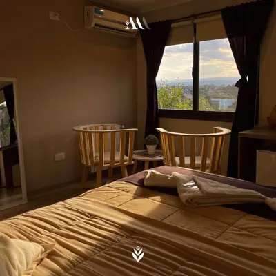a bedroom with a bed and two chairs and a window at Agrippina in Villa Carlos Paz