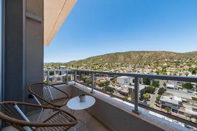 a balcony with two chairs and a table with a view at Edificio Opera en Villa Carlos Paz - Pileta en Terraza e increíbles vistas in Villa Carlos Paz