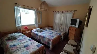 a bedroom with two beds and a tv and a window at La Candelaria in Santa Rosa de Calamuchita