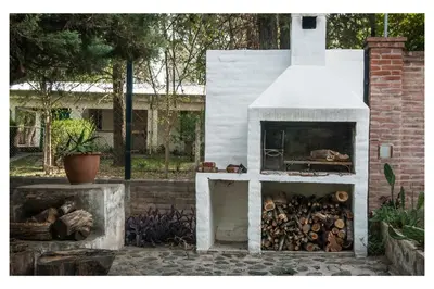 a white outdoor oven with a pile of wood at VILLA BEATRIZ in Villa Anizacate