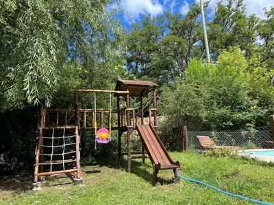 a wooden playground with a slide in a yard at Posada The Gringos in Villa Yacanto