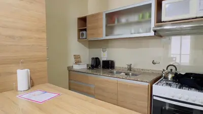 a small kitchen with a sink and a stove at VOW Departamento CÉNTRICO CON COCHERA in Villa Carlos Paz