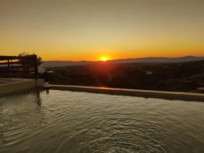 a swimming pool with a sunset in the background at CABAÑAS PIRCAS DE CAMPO in Tanti