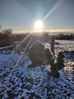 a snow covered field with the sun setting in the background at CABAÑAS PIRCAS DE CAMPO in Tanti