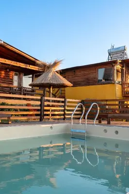 a swimming pool with an umbrella and a house at CABAÑAS PIRCAS DE CAMPO in Tanti