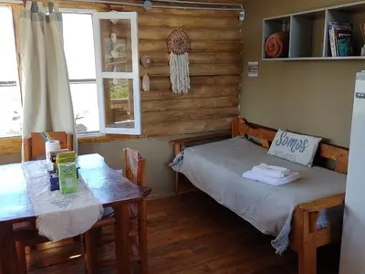 a room with two beds and a table and a window at CABAÑAS PIRCAS DE CAMPO in Tanti