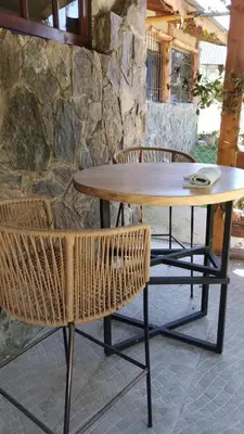 a wooden table with two chairs and a stone wall at Cabañas La Oma Intiyaco in Atos Pampa
