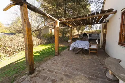 a patio with a table and a wooden pergola at Cabañas La Oma Intiyaco in Atos Pampa