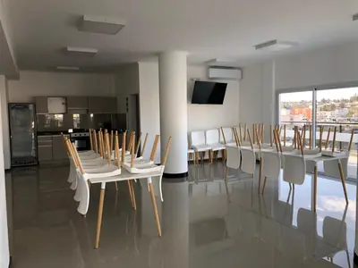 a dining room with white tables and white chairs at Edificio Veneto IV - Departamento de un dormitorio en pleno centro in Villa Carlos Paz
