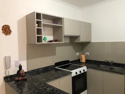 a kitchen with white cabinets and a stove top oven at Edificio Veneto IV - Departamento de un dormitorio en pleno centro in Villa Carlos Paz