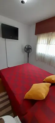 a bedroom with a red bed with a fan at Departamento pleno centro de Villa Carlos Paz in Villa Carlos Paz