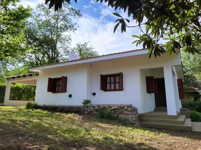 a white house with brown windows and a yard at Otto's Haus in Villa General Belgrano