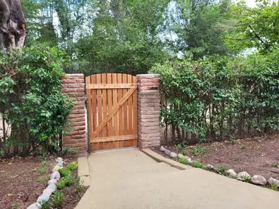 a wooden gate with a brick fence and a sidewalk at Otto's Haus in Villa General Belgrano