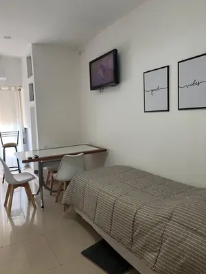 a bedroom with a bed and a desk and a tv on the wall at DERC Temporarios in Río Cuarto