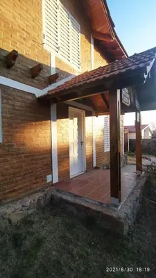 a brick house with a porch and a white door at Cabañas Los Cerezos in Mina Clavero