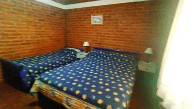 a bedroom with two beds with blue sheets at Cabañas Los Cerezos in Mina Clavero