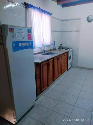 a kitchen with a white refrigerator and a sink at Cabañas Los Cerezos in Mina Clavero