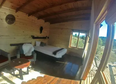 a bedroom in a log cabin with a bed and a table at Fase a Tierra in Atos Pampa