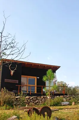a small black house with a stone wall at Fase a Tierra in Atos Pampa
