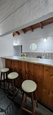 a kitchen with three bar stools and a counter at Chalet exclusivo en Tanti, Córdoba in Tanti