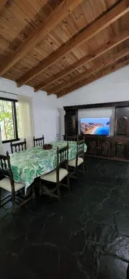 a dining room with a table and a flat screen tv at Chalet exclusivo en Tanti, Córdoba in Tanti