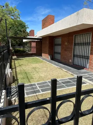 a brick building with a fence in front of a yard at Casa Villa CARLOS PAZ CERCA DE COSTANERA in Villa Carlos Paz