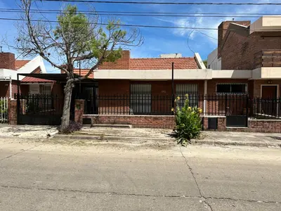 a brick house with a fence and a tree at Casa Villa CARLOS PAZ CERCA DE COSTANERA in Villa Carlos Paz