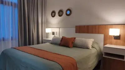 a bedroom with a bed with two lights on the wall at Apart CARLOS PAZ costanera in La Cuesta