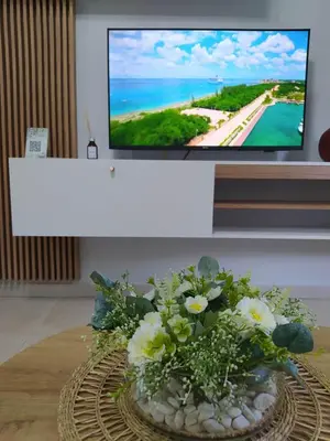 a tv screen with a bouquet of flowers on a table at Apart CARLOS PAZ costanera in La Cuesta