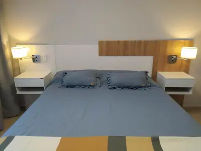 a bedroom with a large bed with blue pillows at Apart CARLOS PAZ costanera in La Cuesta