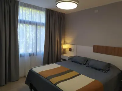 a bedroom with a bed and a large window at Apart CARLOS PAZ costanera in La Cuesta