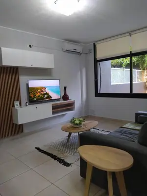 a living room with a couch and a tv on a wall at Apart CARLOS PAZ costanera in La Cuesta