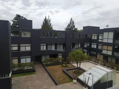 an exterior view of a black building with a courtyard at Apart CARLOS PAZ costanera in La Cuesta