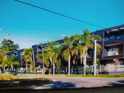 a building with palm trees in front of it at Apart CARLOS PAZ costanera in La Cuesta