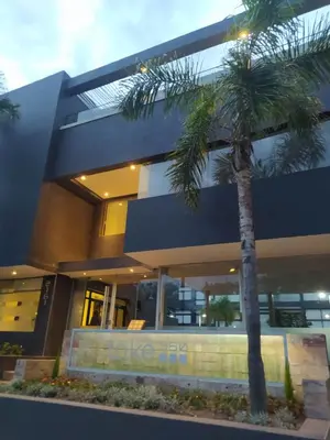 a building with a palm tree in front of it at Apart CARLOS PAZ costanera in La Cuesta