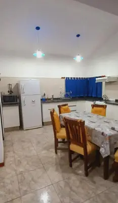 a kitchen with a table and chairs and a kitchen with a refrigerator at La Estancita de Tanti con pileta in Tanti