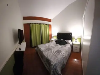 a small bedroom with a bed and a television at La Estancita de Tanti con pileta in Tanti