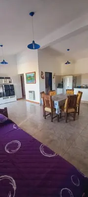 a living room with a table and chairs and a kitchen at La Estancita de Tanti con pileta in Tanti