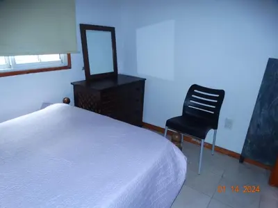 a bedroom with a bed and a chair and a mirror at Cabaña La Chicha in Villa Anizacate