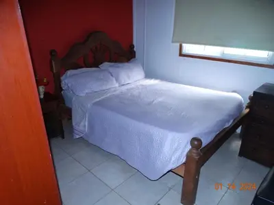 a small bedroom with a bed with white sheets and a window at Cabaña La Chicha in Villa Anizacate