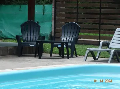 two chairs and a table next to a pool at Cabaña La Chicha in Villa Anizacate