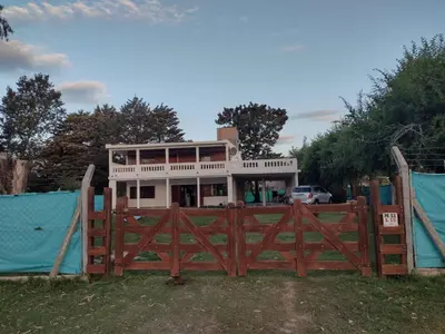 a house behind a wooden fence with a gate at El Abuelo in Santa Rosa de Calamuchita